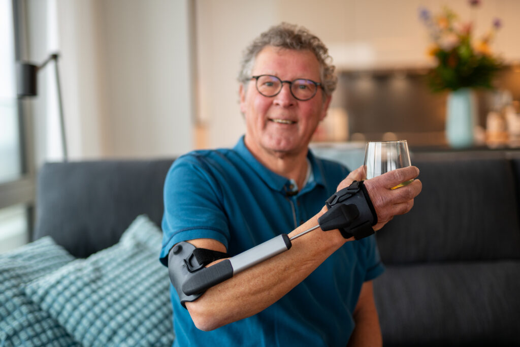 Stil Hand Control™ im Alltag: Tragedauer, Anlegen, Pflege und praktische Tipps 2 Mann trägt die Stil Hand Control Orthese und hält ein Glas in der Hand